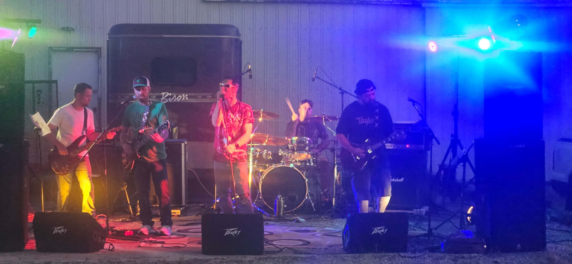 The band mid-set on a barn stage lit blue and pink